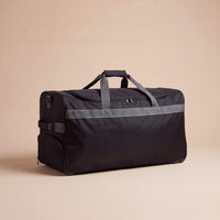 Black duffel bag with reflective stripes on a beige background