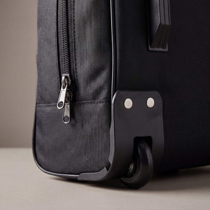 Black suitcase with wheels on a neutral background