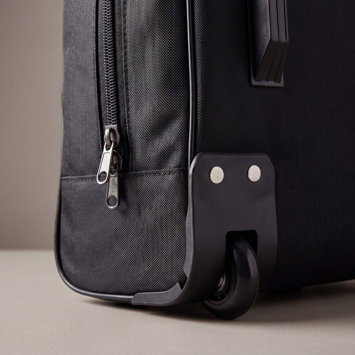 Black suitcase with wheels on a neutral background