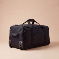 Black travel duffel bag on a beige background