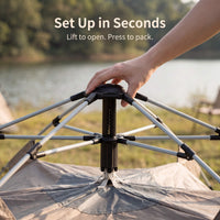 Person setting up a portable tent with text 'Set Up in Seconds' and 'Lift to open. Press to pack.'