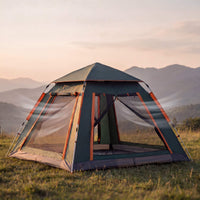 Camping tent in a grassy field with mountains in the background